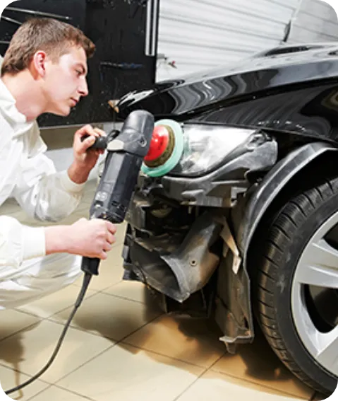 A Man In A White Uniform Repairs A Car In A Bright Garage.