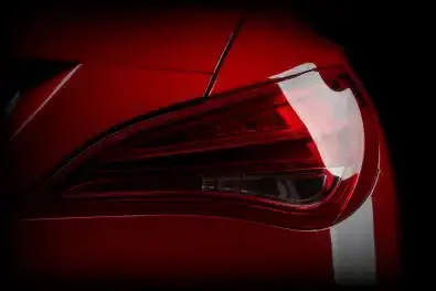 Close-Up Of A Red Car'S Tail Lights, Highlighting Their Bright Illumination And Sleek Design Against A Dark Background.